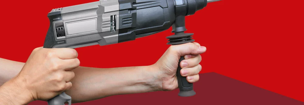 Eine Person hält einen Bohrhammer mit beiden Händen vor einem roten Hintergrund.